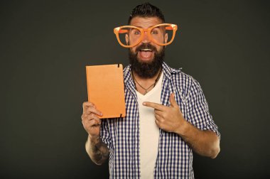 Bir göz atın. Ders kitabı parmakla parti bardaklarda sakallı adam. Üniversite erkek öğrenci ders notları ile. Kitap nerd çalışma. Süslü gözlüklü kitap nerd