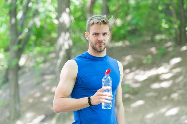 Descansando. Un hombre en ropa deportiva bebe agua. refrescante bebida de vitaminas después del entrenamiento. Hombre atlético con botella de agua. Atleta beber agua después de entrenar en el parque. cuidar la hidratación corporal. deporte y salud — Foto de Stock