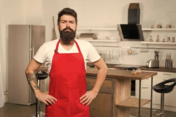 Hur till vända matlagning hemma vana. Mannen skäggig hipster röd förkläde stå i köket. Kök möbler butik. Matlagning i nya köket. Behöver matinspiration. Helgen börjar från välsmakande frukost — Stockfoto