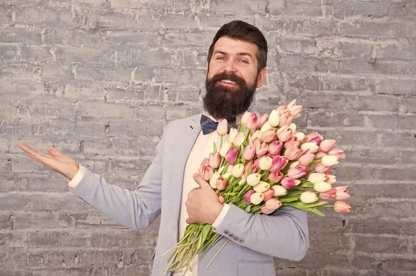 Things that make man gentleman. Romantic man with flowers. Romantic gift. Macho getting ready romantic date. Tulips for her. Man well groomed tuxedo bow tie hold flowers bouquet. From sincere heart