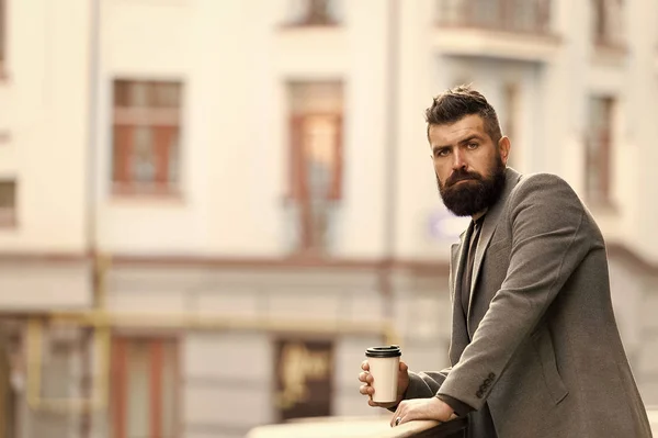 Den právě začal. Podnikatel v hipsterském stylu drží kávu s sebou. Hipster s papírovým kelímkem procházející se po městě. Vousáč si užívá ranní kávu. Hned ráno vypil svůj šálek. — Stock fotografie