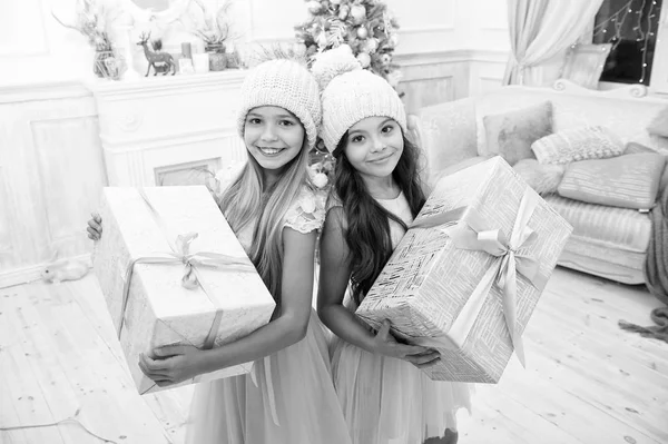 Niños hermanas pequeñas sostienen cajas de regalos fondo interior. Qué gran sorpresa. Pequeñas chicas lindas recibieron regalos navideños. Los mejores juguetes y regalos de Navidad. Niños amigos emocionados desempacando sus regalos — Foto de Stock
