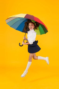 Moda aksesuarı. Şemsiye koruyucu kalkan. Şemsiyeli kız. Yağmurlu gün yürüyüşleri. Mutlu bir çocukluk. Okul zamanı. Gökkuşağı tarzı. Renkli bir hayat. Şemsiyeyle mutlu öğrenci kız. Sonbahar hava tahmini