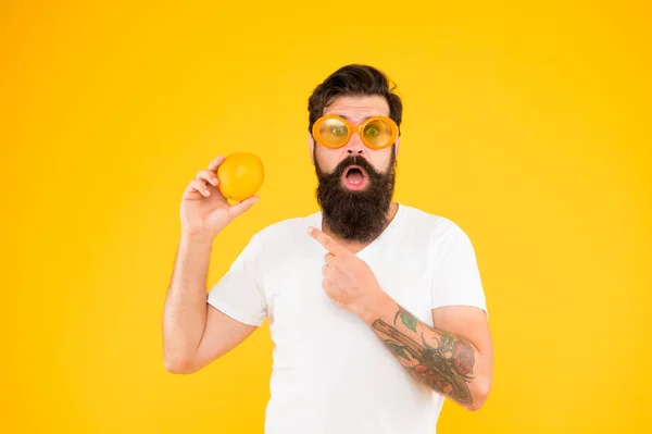 Чоловік бородатий хіпстер в помаранчевих сонцезахисних окулярах на жовтому тлі. Джерело оновлення. Літнє харчування. Хіпстер з бородою в літньому настрої. Веселий хлопець тримає стиглі апельсинові цитрусові. Літні канікули — стокове фото