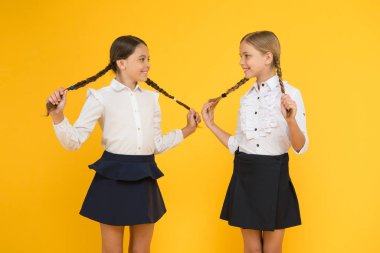 Saç kendiniz yapmak kolay. Sarı arka planda örgülü saçlı sevimli küçük kızlar. Uzun saç örgüleri tutan sevimli küçük çocuklar. Örgü ve okul için saç şekillendirme