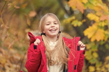 Hayat enerji dolu. Çocuk kız giyim ceket sonbahar sezonu doğa arka plan için. Çocuk sonbahar yürüyüşüne neşeli. Sıcak palto sonbahar için en iyi seçim. Vücut sıcak giysiler sonbahar gün tutun. Sonbahar kıyafeti kavramı