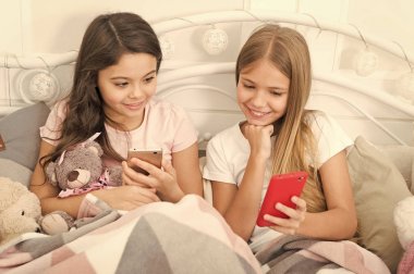 Büyük ve mutlu tatiller. Telefonla manifatura Noel ve yeni yıl tebrik. Cep telefonu ile mutlu küçük çocuklar. Küçük kız yatakta smartphone kullanın. Mutlu Noeller ve mutlu yeni yıl