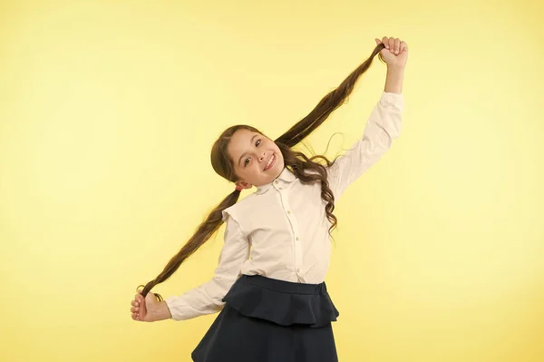 Deal with long hair hairstyle by yourself. Kid girl long ponytail hairstyle. Child school uniform make hairdo. Kid stylish fashionable posing hold ponytails hairstyle. Comfortable and easy hairstyle — Stock Photo, Image