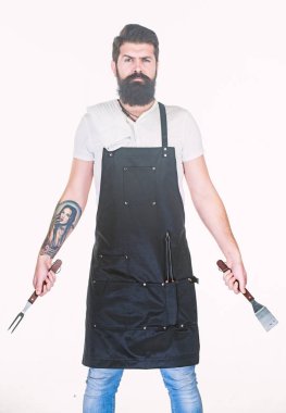 Yemek pişirmek ve servis yapmak için hazır. Elinde çatal ve spatula olan sakallı adam. Barbekü pişirme için mutfak araçları. Paslanmaz çelik mutfak gereçleri tutan hipster. Pişirme aracı seti kullanarak ızgara pişirmek