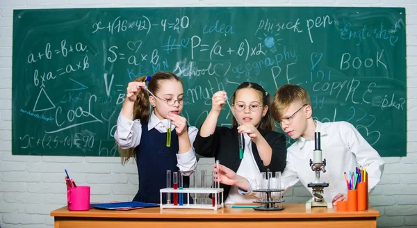 Vetenskaps koncept. Flickor och pojke som ger experiment med vätskor. Provrör med färgglada flytande ämnen. Studier av flytande tillstånd. Grupp skolelever med provrör studerar kemiska vätskor — Stockfoto