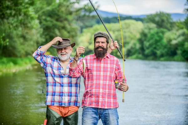 Pescador con caña de pescar. Actividad y hobby. Pesca de agua dulce lago estanque río. Hombres barbudos capturando peces. Hombre maduro con amigo pescando. Vacaciones de verano. Gente feliz y alegre. Tiempo en familia —  Fotos de Stock