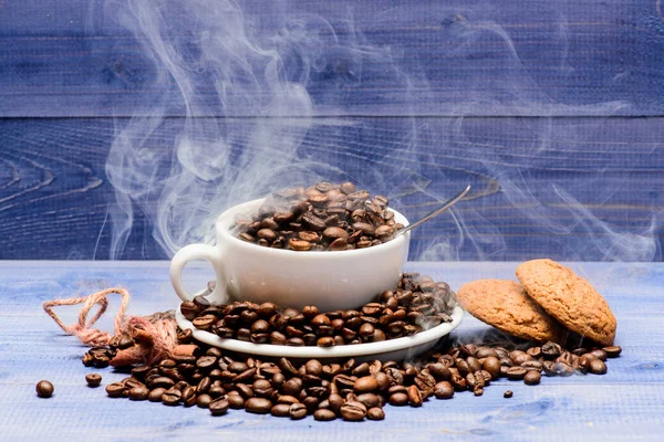 Caffè per l'ispirazione e carica di energia. Grado di tostatura del grano. Menù bevande caffè. Chicchi di caffè tostati freschi. Coppa pieno caffè marrone arrosto fagioli nuvole bianche di fumo blu fondo di legno — Foto Stock