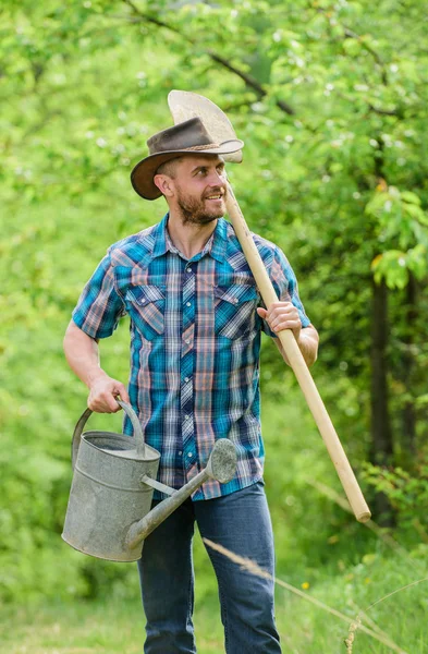 Mogen kille cowboy hatt med vattning kan och spade. Arbor dag. Plantera träd. Engagemang och ansvar. Jordbruks koncept. Plantering i trädgården. Trädplantering tradition. Växande växter — Stockfoto