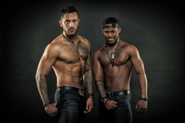 Maço kas dövmeli torsolar ile çekici, koyu arka plan bak. Erkeklik kavramı. Seksi kas torsolar ile çocuklar sporcular. Atletler çıplak kas sandıkları ile kendine güvenen yüzleri