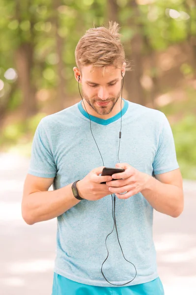 Pairing his fitness watch with his smartphone. Sportsman using fitness tracker for training outdoor. Fit man tracking his fitness activity with sports watch. Monitoring his health with fitness device