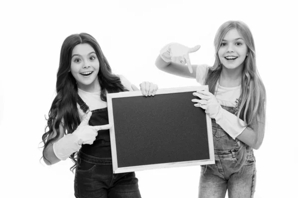 Un poco de ayuda para mantener las cosas ordenadas. Adorables colegialas ordenadas con guantes de goma apuntando a la pizarra ordenada. Niños de primaria manteniendo sus útiles escolares limpios y ordenados, espacio para copiar —  Fotos de Stock