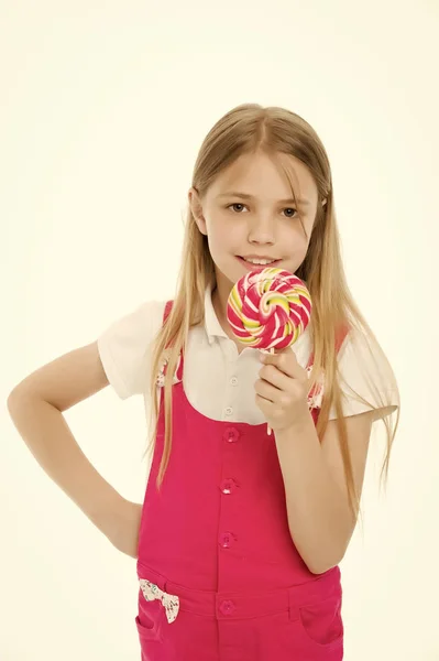 Doux regard. Petite fille manger des bonbons sur bâton isolé sur blanc. Sourire d'enfant avec sucette. Joyeux gosse au caramel tourbillonnant. Nourriture et dessert. Régime alimentaire et régime — Photo