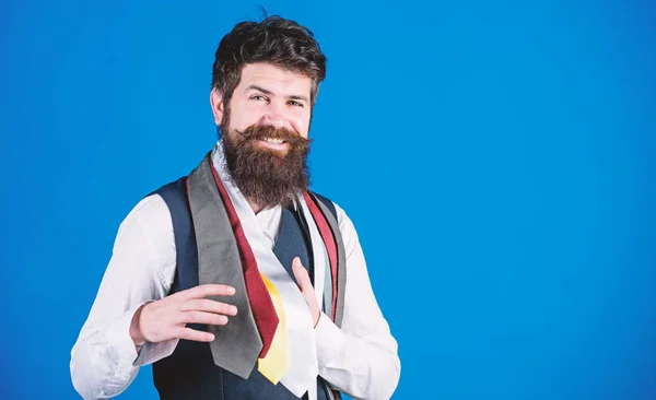 He is fond of shopping. Happy shop assistant offering wide choice of neckties for shopping. Bearded shopper choosing necktie in shopping mall. Hipster shopping the latest tie collection, copy space