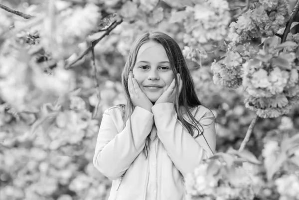 Remedio para la alergia. El niño disfruta de la vida sin alergia. Huele flores. Chica disfrutando de aroma floral. Concepto de alergia al polen. A los niños les gusta el sakura de flor de cerezo. Niño sobre flores rosadas sakura fondo del árbol —  Fotos de Stock