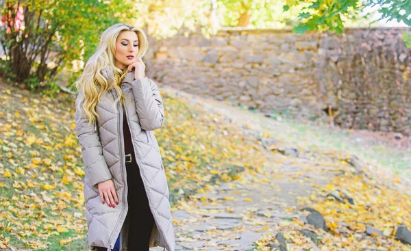 Puffer jacket casual and comfortable style. Girl fashionable blonde walk in autumn park. Woman wear warm grey jacket. Jacket everyone should have. Puffer fashion trend concept. Oversized jacket trend