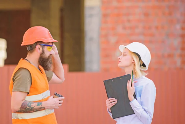 Construction industry concept. Relationships construction client and participant building industry. Discuss progress plan. Woman engineer and bearded brutal builder discuss construction progress