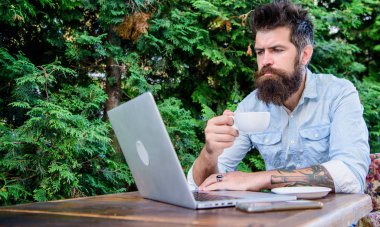 Online rezervasyon daire. Adam sakallı hipster dizüstü bilgisayar sörf internet ve kahve içme ile açık havada oturup. Adam daire arıyor. Tatil veya tatil için daire bulun. Tatil planlama