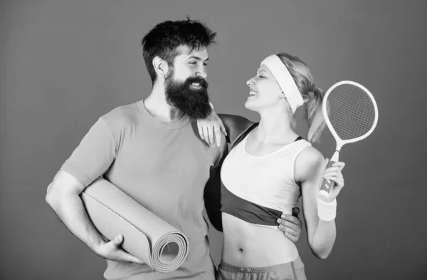 We are all in this together. Sport couple. Happy woman and bearded man workout in gym. Sporty couple training with fitness mat and tennis racket. Strong muscles and body. Athletic Success. love sport