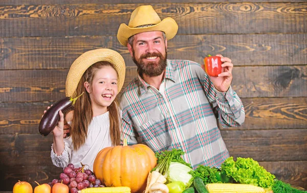 Man bearded rustic farmer with kid. Countryside family lifestyle. Family father farmer gardener with daughter near harvest vegetables. Farm market with fall harvest. Family farm festival concept
