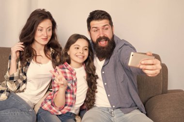 Smartphone için selfie kullanın. Dostu aile birlikte eğleniyor. Anne baba ve kızı kanepede rahatlatıcı. Aile fotoğrafı için poz. Mutlu anları yakalayın. Aile selfie. Aile birlikte hafta sonu geçirmek