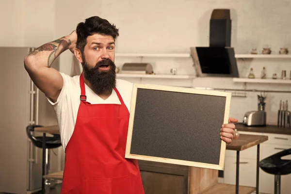 Concepto hacks cocina. Maneras inteligentes de organizar la cocina. Cocine mantenga en blanco espacio de copia de pizarra. Consejos secretos. Información útil. Hombre barbudo delantal hipster rojo de pie en la cocina. Tienda de muebles de cocina —  Fotos de Stock