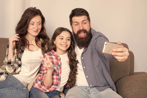 Smartphone için selfie kullanın. Dostu aile birlikte eğleniyor. Anne baba ve kızı kanepede rahatlatıcı. Aile fotoğrafı için poz. Mutlu anları yakalayın. Aile selfie. Aile birlikte hafta sonu geçirmek — Stok fotoğraf