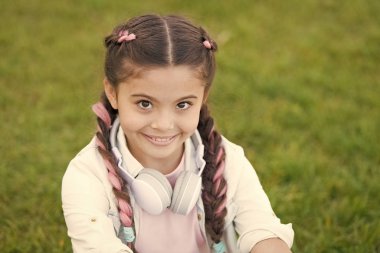 İyi tarafından bak. Secrets yükselterek mutlu bir çocuk için. Kız sevimli yeşil çim arka plan. Açık havada rahatlatıcı sağlıklı duygusal mutlu bir çocukluk. Kendinizi mutlu olsun. Kız modern kulaklık zevk rahatla