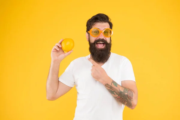 Чоловік бородатий хіпстер в помаранчевих сонцезахисних окулярах на жовтому тлі. Веселий хлопець тримає стиглі апельсинові цитрусові. Літня відпустка. Джерело оновлення. Літнє харчування. Хіпстер з бородою в літньому настрої — стокове фото