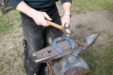 Demirci örs üzerinde çekiçle at nalı döver. Antik zanaat. Köy teknesi. Demirci metal çalışıyor. Atölyede zanaat için araçlar. Demirci meslek kavramı