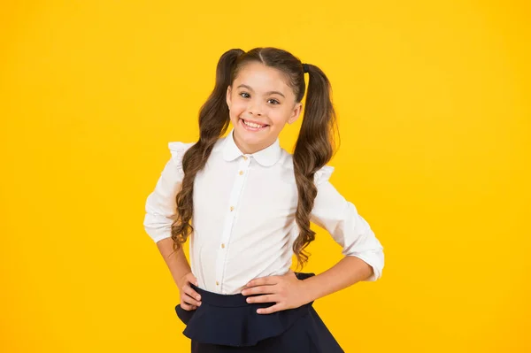 Κομψό και σικ. Κομψή μαθήτρια. Ευτυχισμένο μικρό παιδί με κομψή εμφάνιση σε κίτρινο φόντο. Μικρό κορίτσι με μακριά μαλλιά χαμογελαστά σε κομψό σχολείο στολή — Φωτογραφία Αρχείου