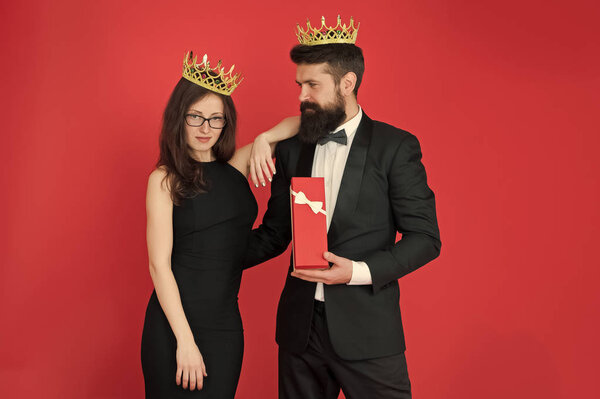 Royal gift. Queen of his heart. Man bearded king in tuxedo golden crown giving gift box to woman elegant dress. Royal family. Couple in love royal family. Elite society. King and queen formal event