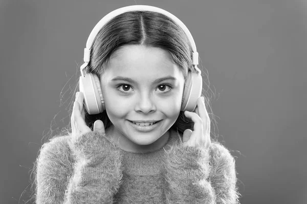 Modern music is her life style and pleasure. Little modern girl wearing bluetooth headphones. Small child listening to music in everyday life. Using modern technology in daily life. Modern life