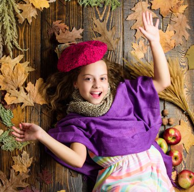 Çocuk kız parlak yumuşak örme şapka sonbahar tadını çıkarın. Sonbahar moda şapka aksesuarı. Moda trendi sonbahar sezonu. Kız ahşap arka plan düşmüş akçaağaç yaprakları üst görünümü yatıyordu. Şapka aksesuar moda detay