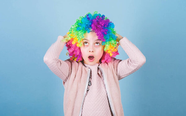 Circus school concept. Acting school for children. Develop acting talent into career. Girl artistic kid practicing acting skills. Kid colorful curly wig artificial hair clown style blue background