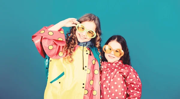 Chicas pequeñas en impermeable y gafas. niñas pequeñas felices en abrigo de lluvia colorido. protección contra la lluvia. Arco iris. moda de otoño. niños hipster alegres, hermandad. divirtiéndose. La mejor manera de pasar las vacaciones —  Fotos de Stock