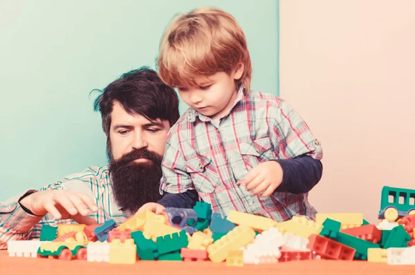 Desarrollo y crianza infantil. Padre e hijo diviértanse. Importancia de jugar juntos. El hipster barbudo y el chico juegan juntos. Papá y su hijo construyen bloques de plástico. Concepto de cuidado infantil. Familia feliz —  Fotos de Stock