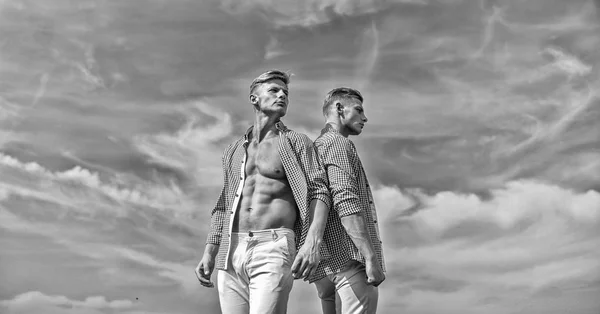 Men strong athlete wear same shirts. Brothers twins looks attractive. Fashionable similar outfits. Men twins brothers muscular guys posing in shirts sky background. Menswear and fashion concept