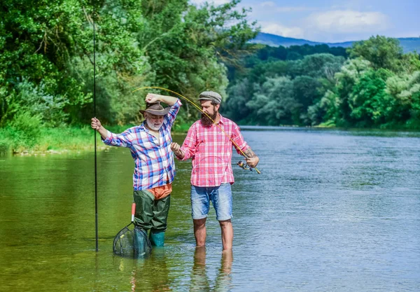 Pesca d'acqua dolce lago stagno fiume. Uomo maturo con amico pesca. Vacanze estive. Felice gente allegra. Pescatore con canna da pesca. Uomini barbuti che catturano pesci. Tempo in famiglia. Attività e hobby — Foto Stock