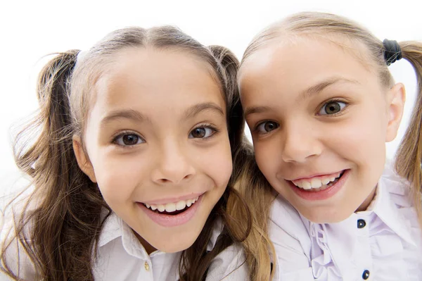 Een hele nieuwe look. Gelukkige schoolmeisjes. Schattige kleine meisjes die glimlachen geïsoleerd op wit. Basisschoolmeisjes met charmante glimlachen en lange paardenstaarten. Leuke meisjes klasgenoten. selfie maken — Stockfoto