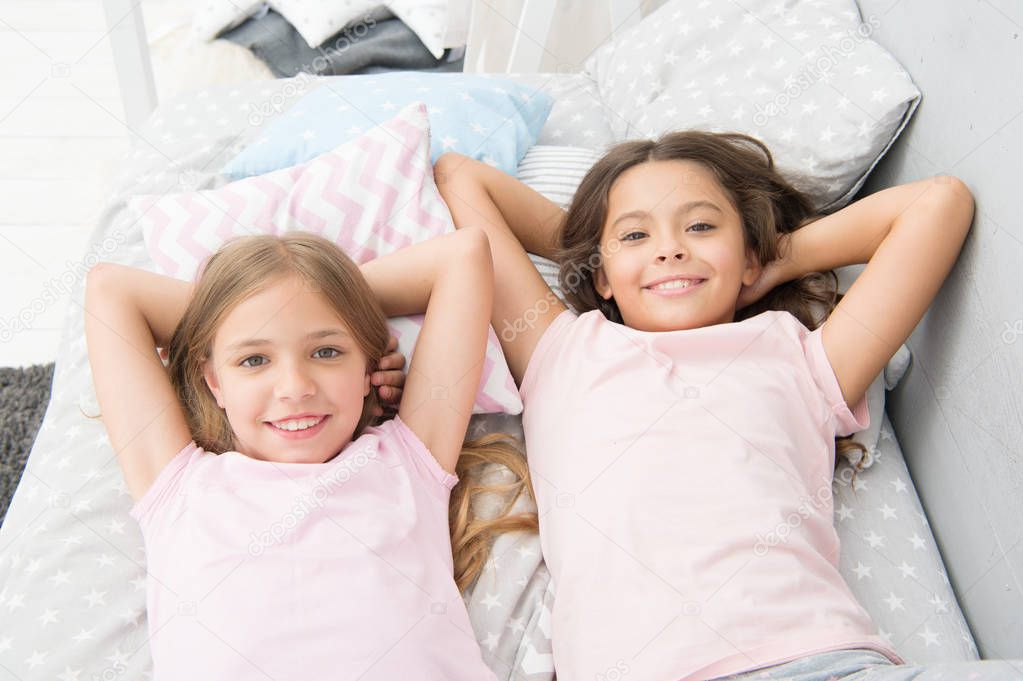 Being as happy as the day is long. Happy little girls having afternoon nap in bedroom. Adorable small children relaxing on bed. Enjoying happy childhood. Carefree and happy