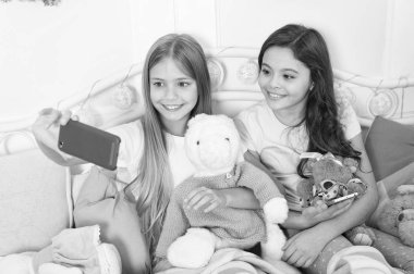 Noel ve yeni yıl selfie smartphone ile alıyor. Küçük kızlar yatakta telefon kullanın. Mutlu Noeller ve mutlu yeni yıl tebrik. Cep telefonu ile mutlu küçük çocuklar. Kendi fotoğraf