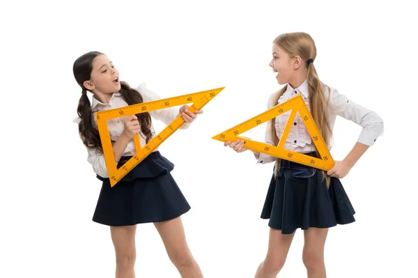 Урок на будущее. Маленькие дети с измерительными приборами на школьном уроке. Девочки готовятся к уроку геометрии. Милые школьницы держат треугольные правители для урока — стоковое фото