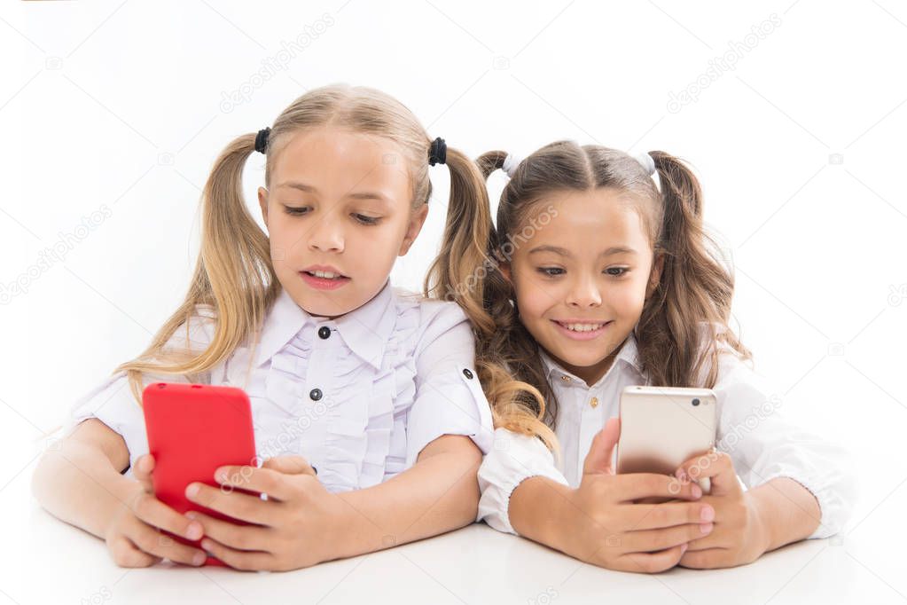 Smart pupils. Little pupils texting message during class isolated on white. Cute lyceum pupils diving deep into smartphone lessons. Small pupils using mobile phones in classroom