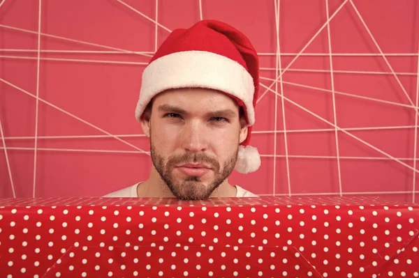 サンタはあなたのためのギフトを持って来る。男の魅力的なサンタ クロースは、大きな箱を運ぶ。あなたのギフトを展開する準備ができました。クリスマスの休日のお祝い。男ハンサムなひげを剃っていないサンタ帽子は、ギフト ボックスを保持します。クリスマス ギフトの概念 — ストック写真