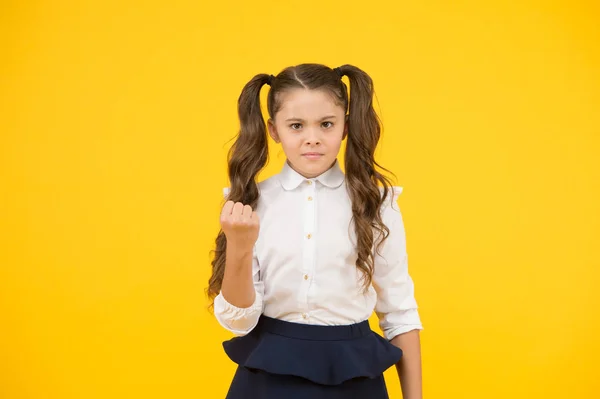 Tão zangado. Criança descontente com a escolaridade. Menina da escola pequena gesticulando seu punho com raiva no fundo amarelo. Não gosto da escolaridade obrigatória. Ter educação privada. Anos lectivos — Fotografia de Stock